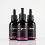 Three black bottles labeled 'oilgasm' on a light gray background