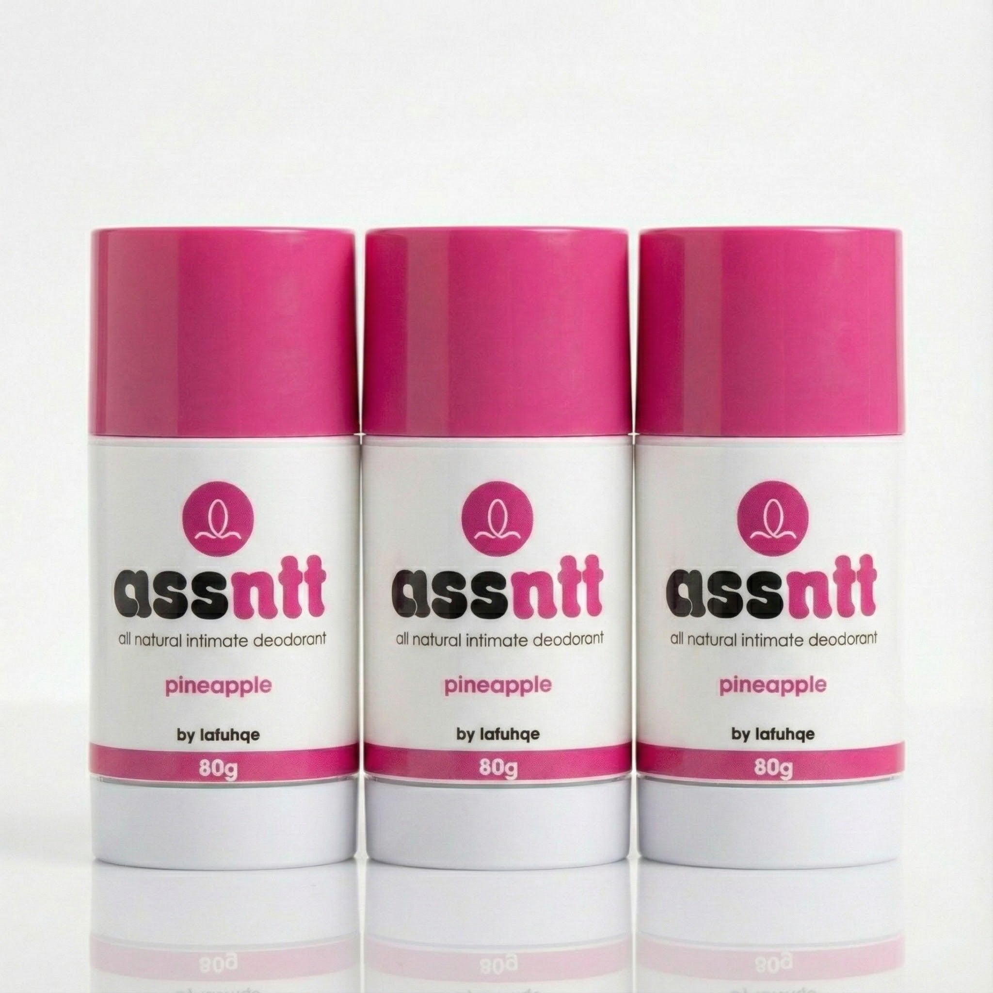 Three bottles of 'assntt' all natural intimate deodorant with pink caps on a white background.